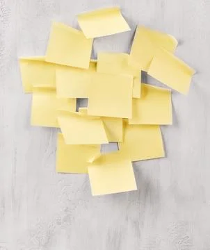 Blank yellow sticky notes clustered on a gray wall for a task list Stock Photos
