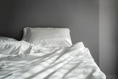 The blankets on the crumpled mattress in the empty dark bedroom Fotos Stock