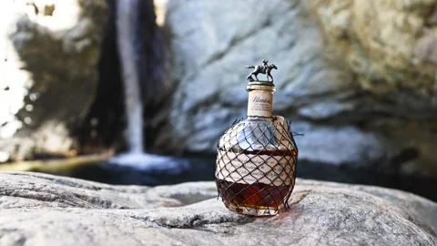 Blanton's Bourbon Bottle with a Scenic Waterfall Backdrop in Nature Stock Footage 295980568