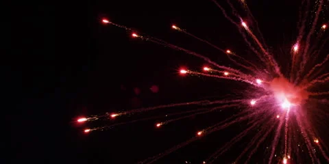 A blast of pink fireworks explodes at the right, shooting comets of debris Vídeos de archivo 59125108