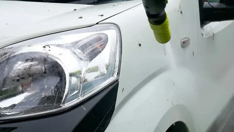 Blasting off mud spots from the side of a white van with a pressure washer Stock Footage 321037047