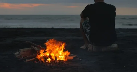 Blazing campfire with bright flames on the black sand beach at sunset. Video stock 123393281