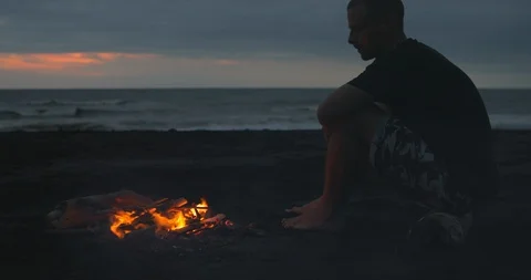 Blazing campfire with bright flames on the black sand beach at sunset. Stock-Footage 123399522