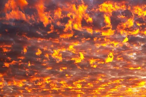 Blazing clouds against the backdrop of the setting sun Stock Photos