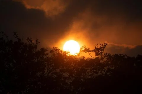 A Blazing Orb of Sun Setting Behind Smoky Clouds, Highlighting the Intensit.. Foto stock