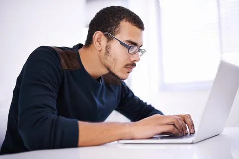 Blazing through lines of code with ease. a handsome young man working on his Stock Photos