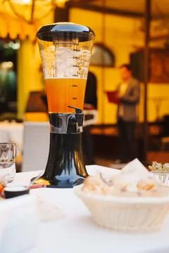 Blender with orange drink on table in restaurant setting during evening Stock Photos
