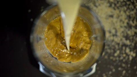 In a blender, pour a stream of milk on almonds, nuts, coffee, cocoa, Cola and on Stock Footage 129760316