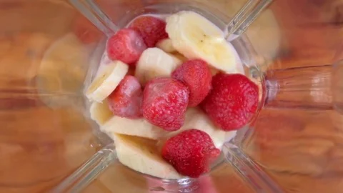 Blender with strawberries and bananas is making smoothie Stock Footage