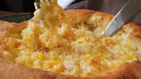 Blending cheese and egg in hot Adjarian Khachapuri in a cozy restaurant Vidéo 286056574