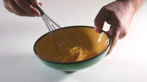Blending fresh eggs with a whisk tool in a bowl in slow motion. Cooking conce Stock Footage 123884745