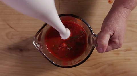 Blending hot tomato sauce with a hand blender; top-shot / high-shot Stock Footage 64046821