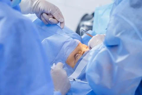 Blepharoplasty suturing under local anesthesia in a sterile operating room Stock Photos