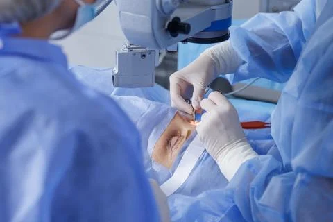 Blepharoplasty under operating microscope with gloved surgeons and sterile .. Stock Photos