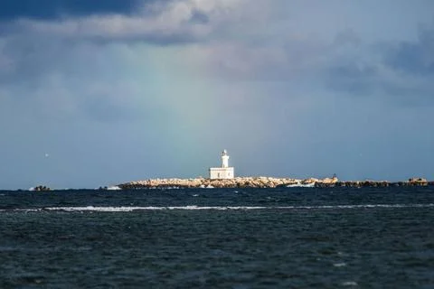  Blick auf einen Leuchtturm hinter dem sich ein Regenbogen gebildet hat. T... Stock Photos