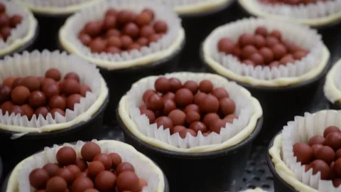 Blind baking mini tartlet crusts with ceramic pie weights close up Stock Footage 343018258
