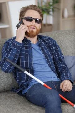 Blind man with disability using digital assistant on mobile phone Stock Photos