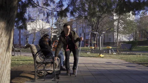 Blind man sitting on park bench. He folds his cane. Stock Footage 228822339