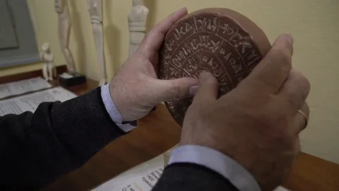 Blind man touching a copy of the Phaistos Disc dating from the Minoan Bronze Stock Footage 140989220