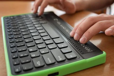 A blind man uses a computer with a Braille display and a computer keyboard Foto stock