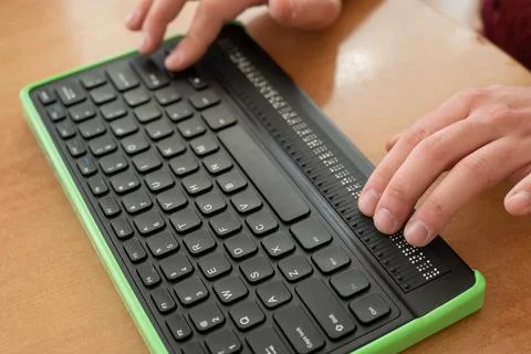 A blind man uses a computer with a Braille display and a computer keyboard Stock Photos