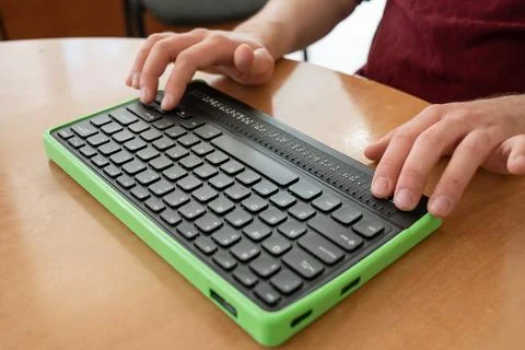 A blind man uses a computer with a Braille display and a computer keyboard Stockfoto's
