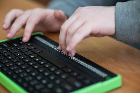 A blind man uses a computer with a Braille display and a computer keyboard Foto stock
