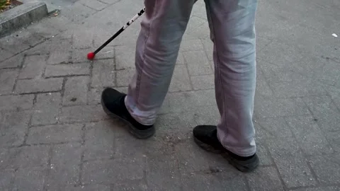 A blind man walks down the street with a cane. A blind person Stock Footage 295677879
