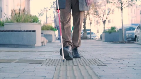 Blind person using white cane on straight tactile tiles to navigate road Stock Footage 220838633