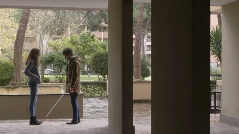 Blind young man walking with his stick, meets her girlfriend- outdoor Stock Footage 119974636