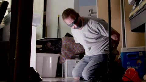 Blindfolded &amp; bound man / hostage held in cluttered garage as criminal ransom 스톡 동영상 153717861