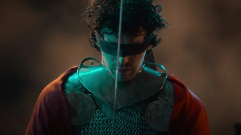 Blindfolded Man in Medieval Armor Holding Glowing Fantasy Sword Stock Footage 345513957