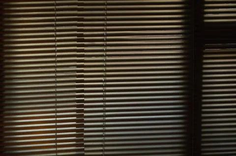 Blinds on the window, sunlight breaking through the blinds, dark room Fotos de archivo