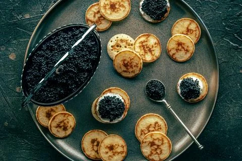 Blinis with caviar, overhead flat lay shot on a festive dish, mini pancakes Foto stock