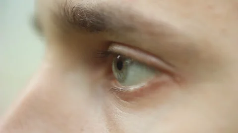 Blinking male eye close up. pensive sad look ahead macro. Half face of a man on Stock Footage 106989887