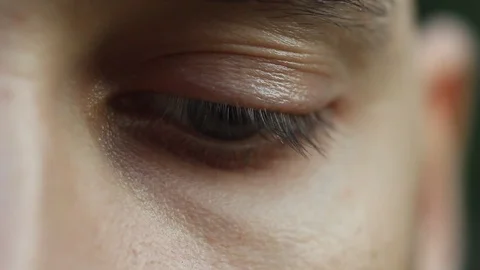 Blinking male eye close up. pensive sad look down and into the macro. Half face Stock Footage 106989968