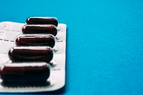 Blister pack of dark red capsules on a blue background Stock Photos