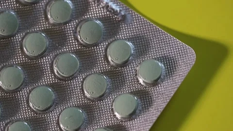 Blister pack with pills slowly rotating on yellow background Video stock 306074348