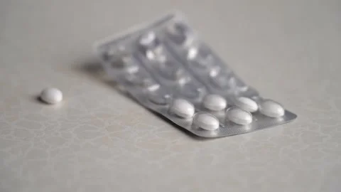 Blister with white tablets falls on table and the pills fly to sides 動画素材 233821727