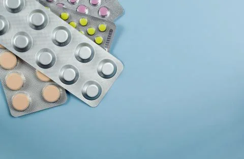 Blisters of tablets on a blue background. Top view, close-up Stock Photos
