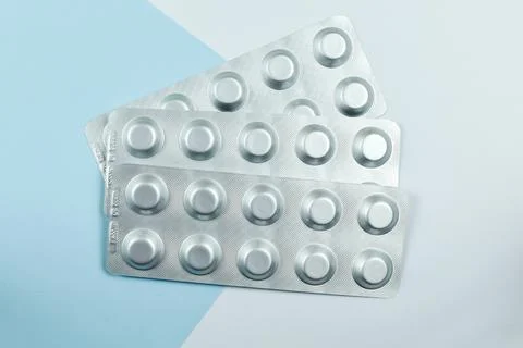 Blisters of tablets on a blue-white background. Top view, close-up Stock Photos