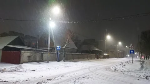 Blizzard against the backdrop of lights on poles in the city in winter at night Stock Footage 295106882
