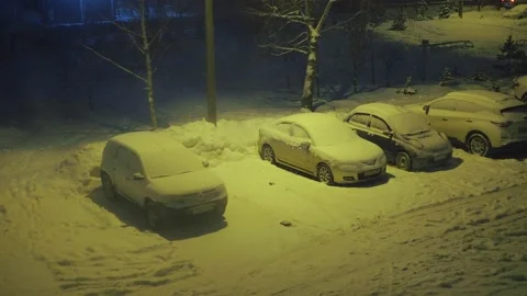 A blizzard outside the window in the parking lot with cars. illuminated by a Stock Footage 169708246