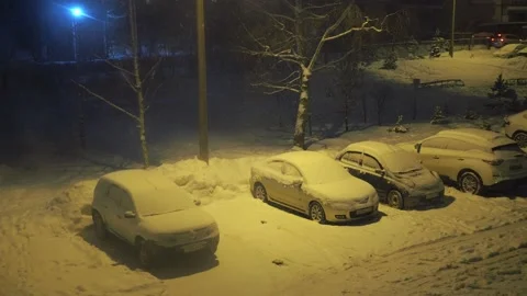 A blizzard outside the window in the parking lot with cars. illuminated by a Stock Footage 169947128