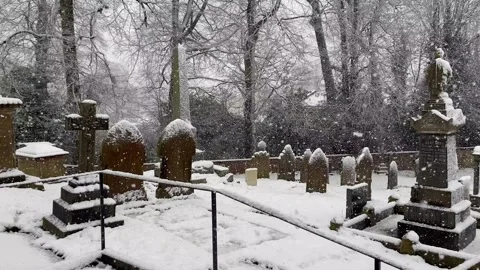 Blizzard snowfall cemetry churchyard burial ground gravestones Stock Footage 298974278