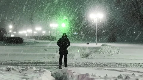Blizzard snowstorm at night, man walks through pedestrian crossing during heavy Video stock 326749784