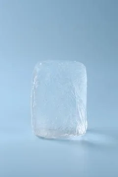 Block of clear ice on light blue background 스톡 사진