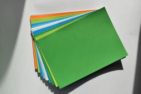 Block of colored A4 sheets on a green color illuminated by the sun 스톡 사진