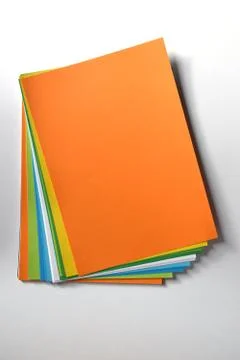 Block of colored A4 sheets on a orange color illuminated by the sun 스톡 사진