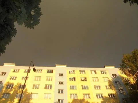 Block of flats under storm cloud covered sky,but illuminated by sun Stock Photos